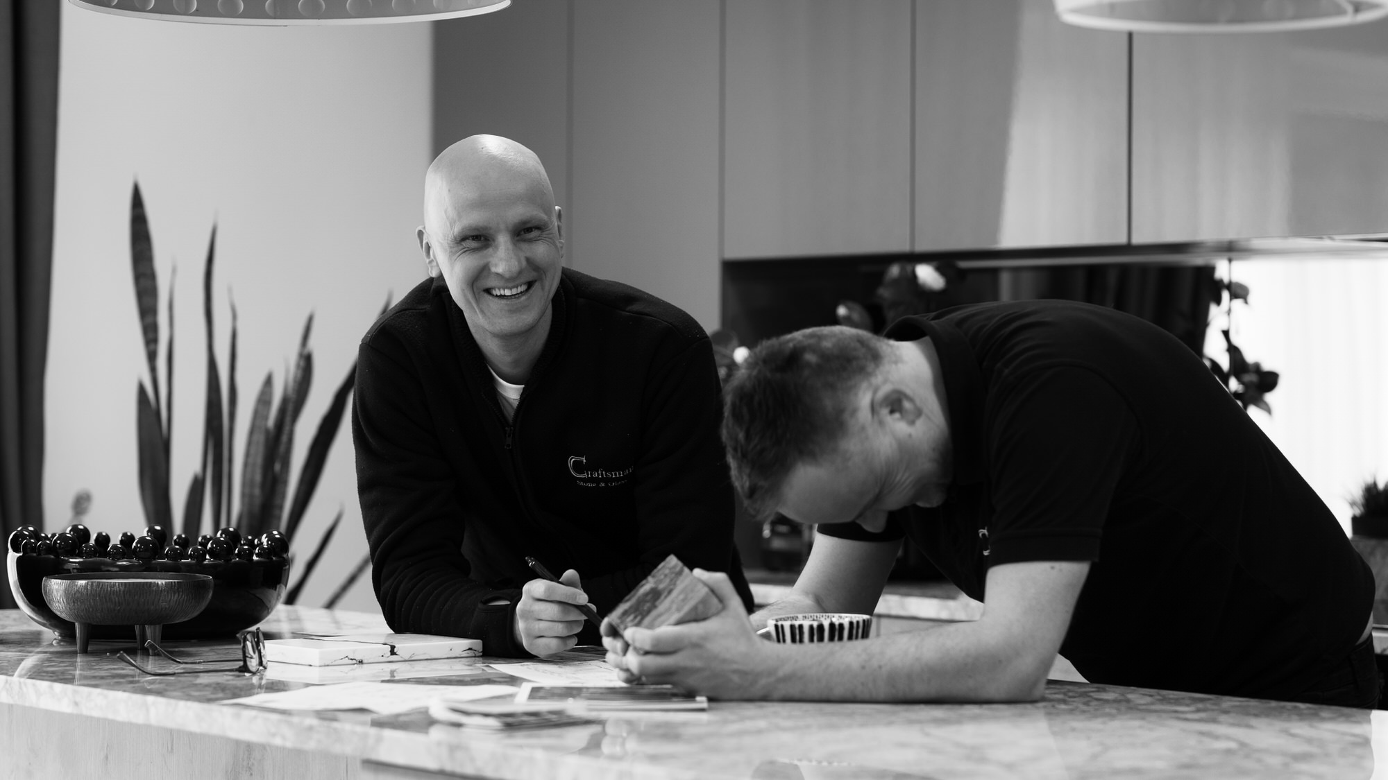 Black and White of Stone Masons - standing in a kitchen and discussing client projects